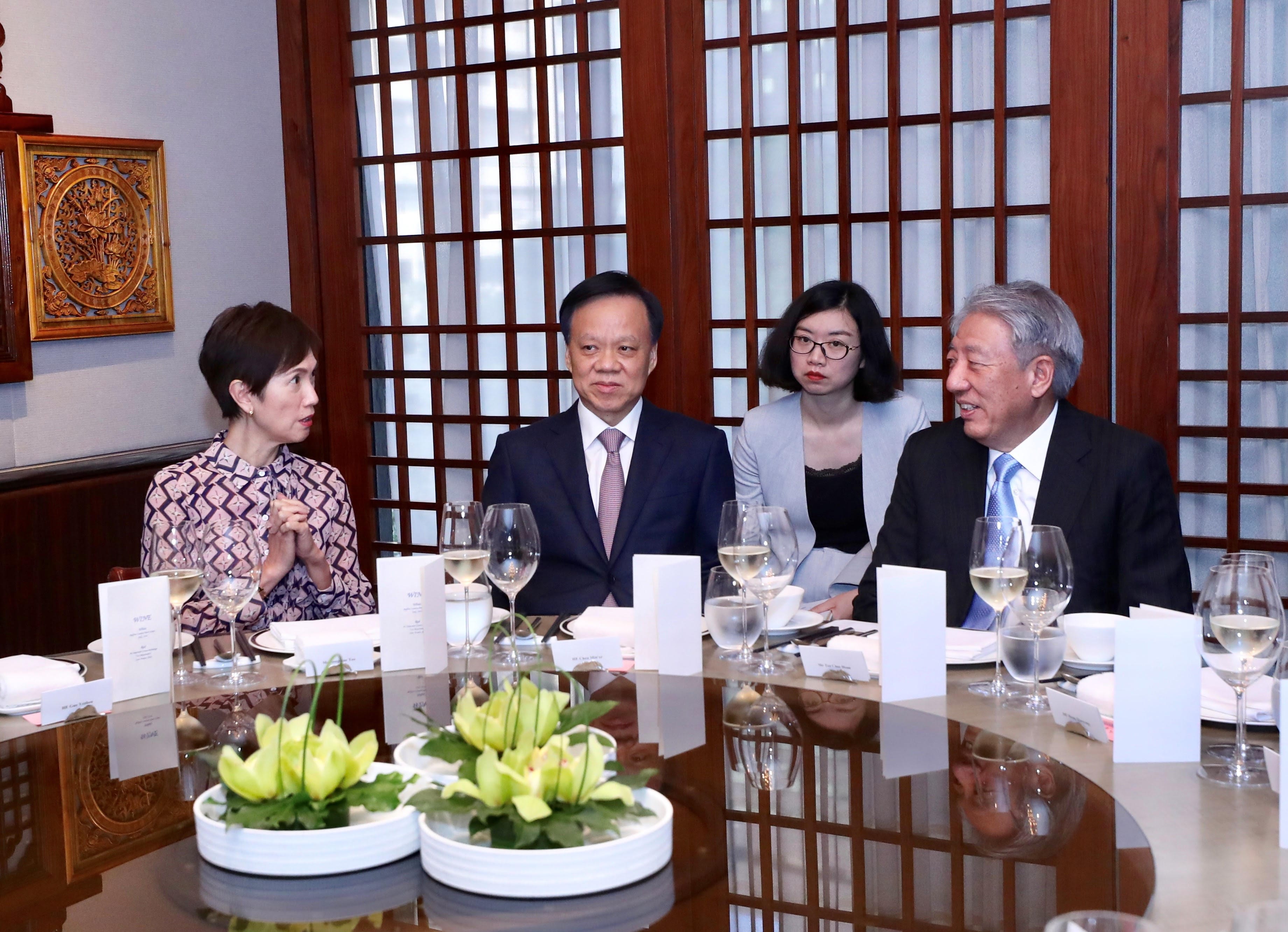 Two men in suits shaking hands; Singapore flag visible.